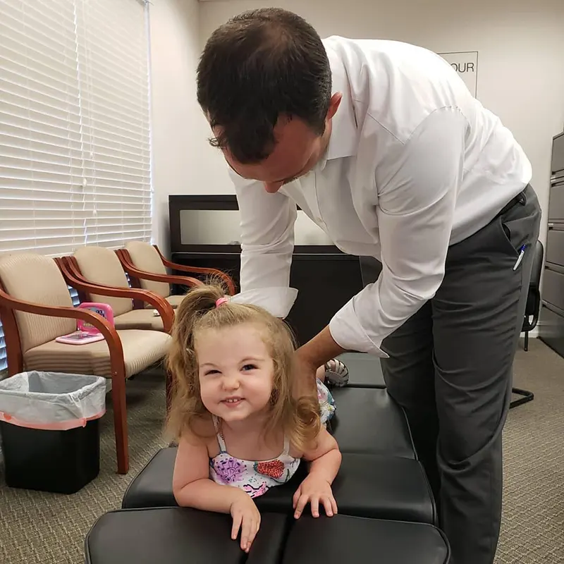 Chiropractor Dr. Dane Cunningham of Mother Goose Chiropractic in Bonita Springs, FL Performing Child Chiropractic Adjustment.